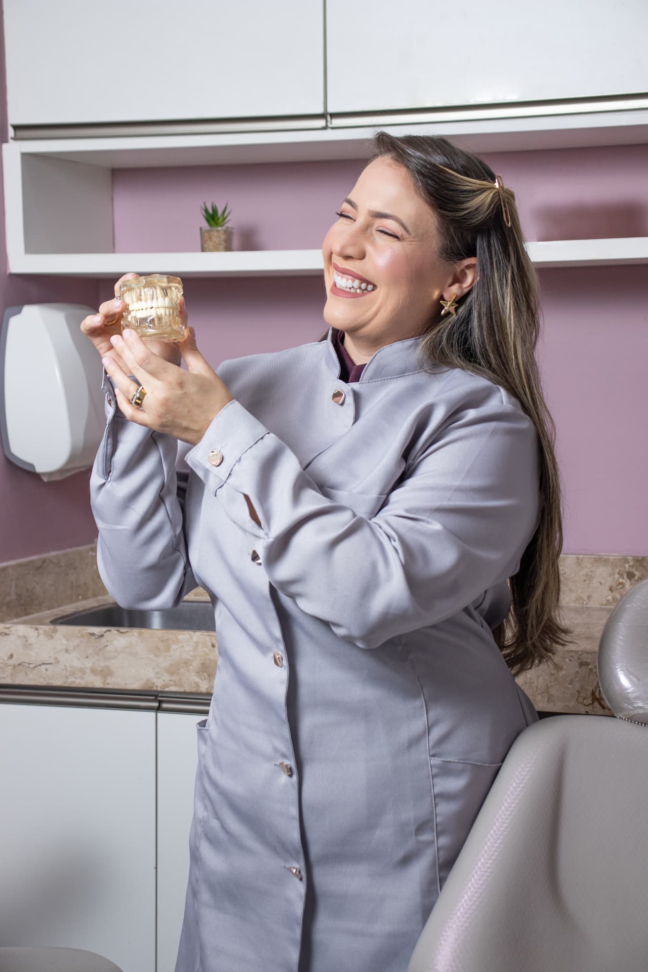 Dra. Júlia Moura Rosetti segurando modelo de arcada dentária na DS Clinic em Fortaleza